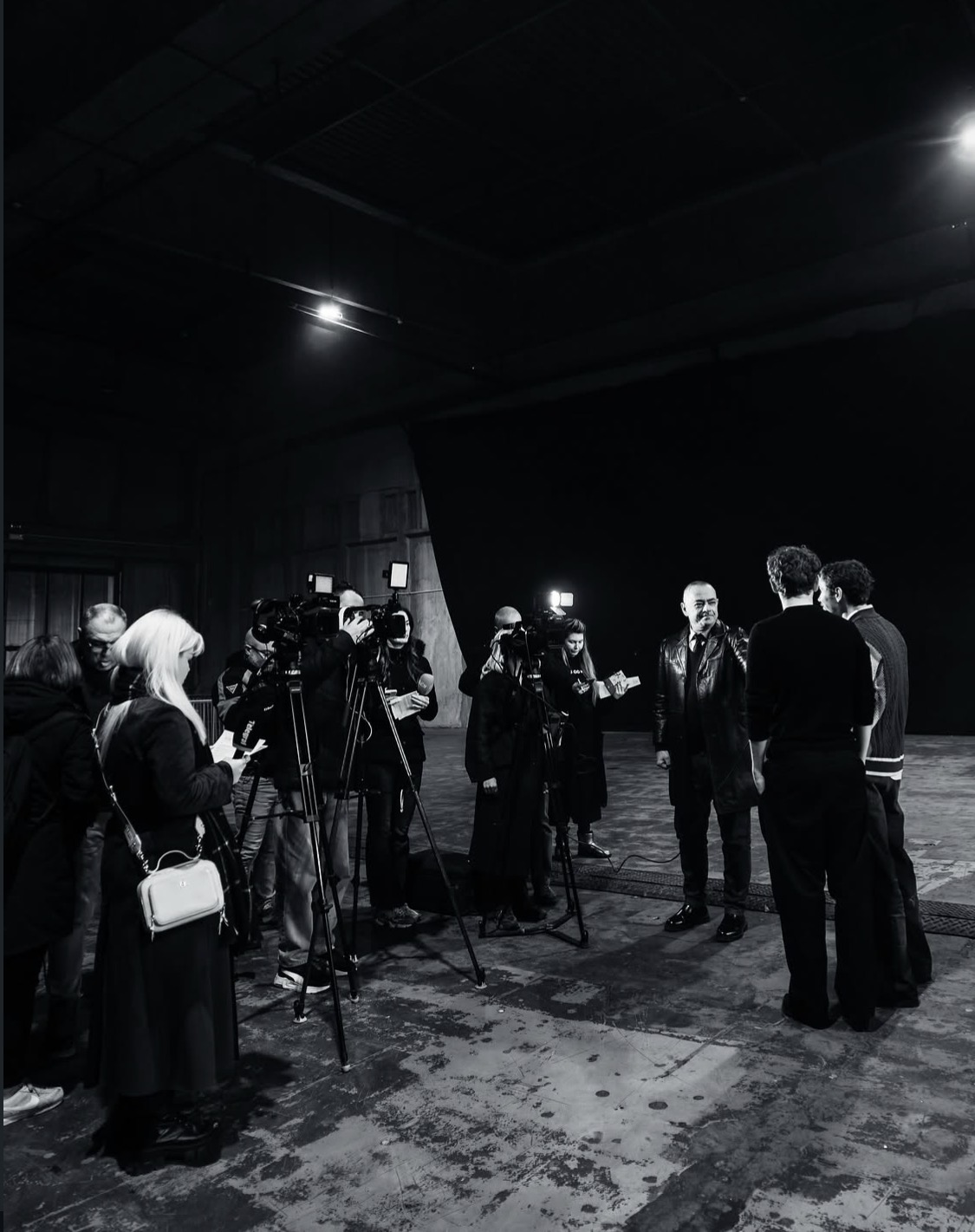 A media press call with cameras and reporters in a rehearsal hall