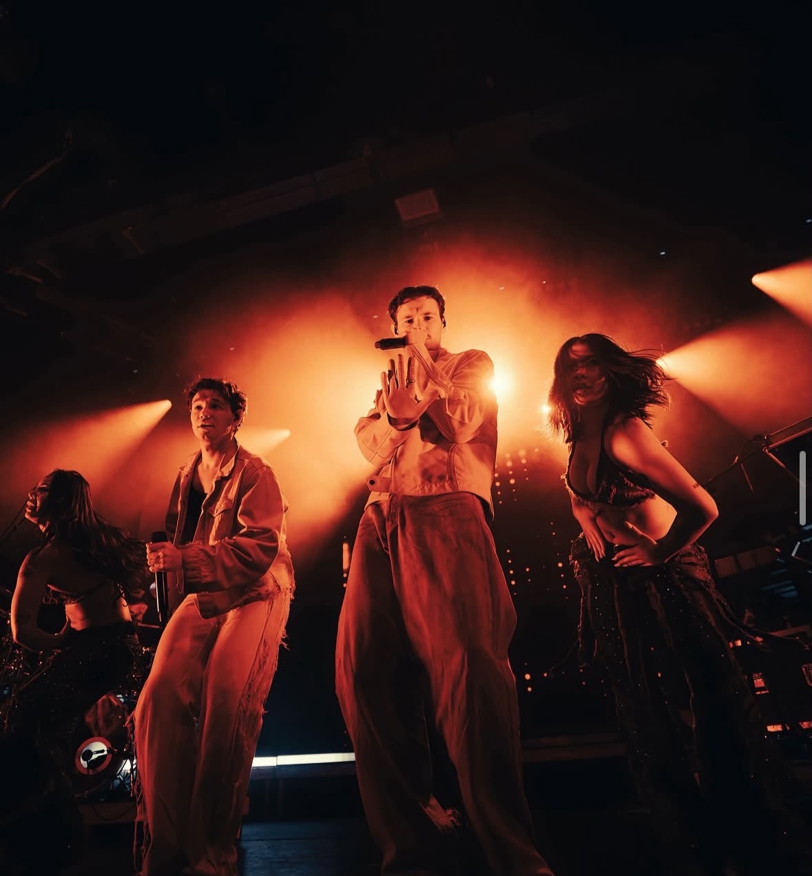 Marcus & Martinus dancing with two dancers on a stage lit in warm orange haze