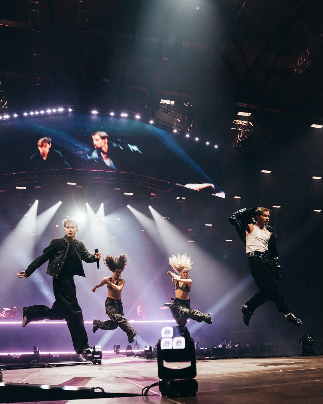 Marcus & Martinus and two dancers leaping mid-air across an arena stage